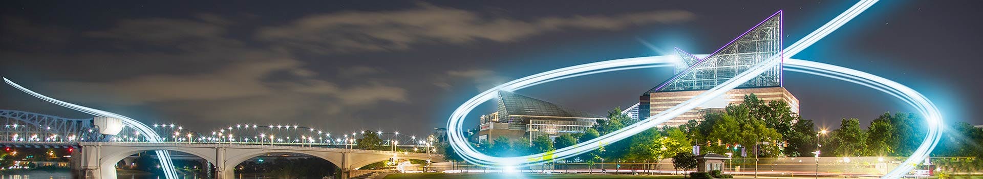 View of the Tennessee Aquarium at night from across the river with fiber light streaks in sky