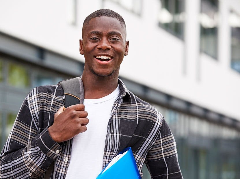 Student with backpack and notebook smiling