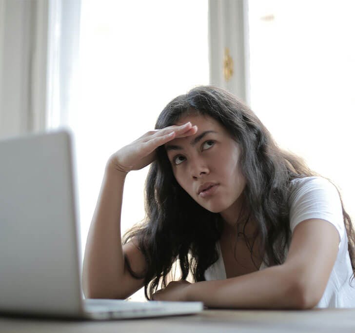 Woman sitting in front on computer thinking.