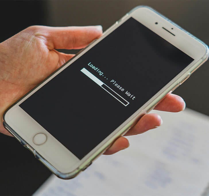 A hand holding a phone that shows a buffering bar due to slow internet.