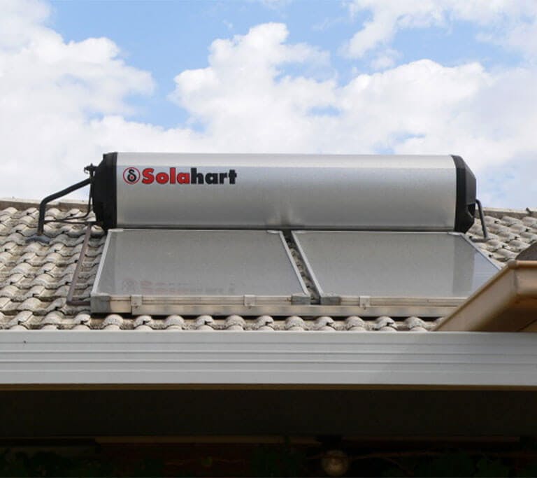 A Solahart brand solar hot water panel and integrated tank on a house roof in Australia.