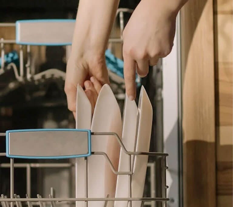Someone loading an automatic dishwasher.