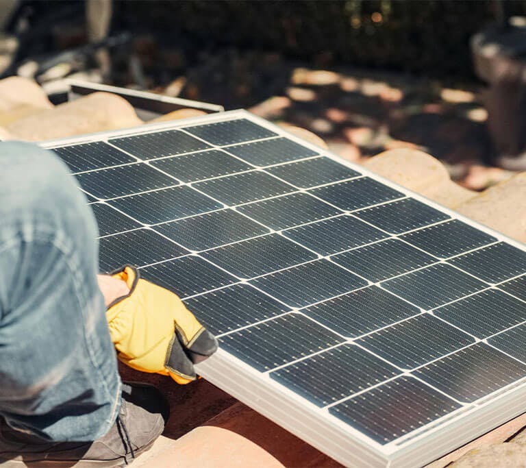 A person with gloves on is on the roof trying to determine the best angle for their rooftop solar panels.