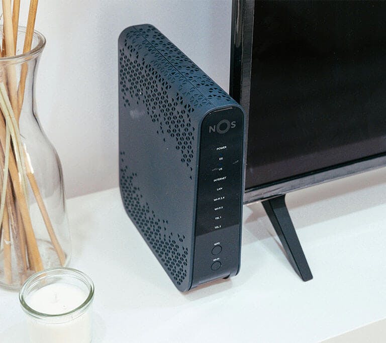 Close-up of a router, a computer monitor, and a set of incense sticks arranged on a desk.