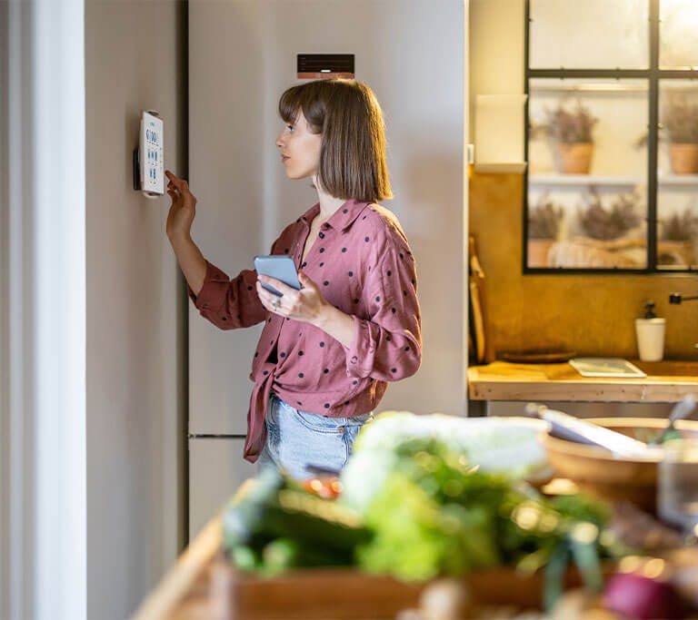 Woman setting up smart home thermostat