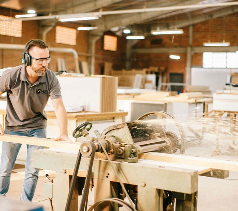 A worker operates industrial woodworking equipment in a commercial shop.