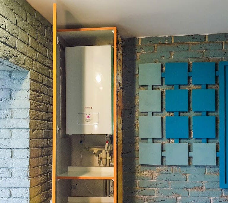 A tankless water heater in a brick room.