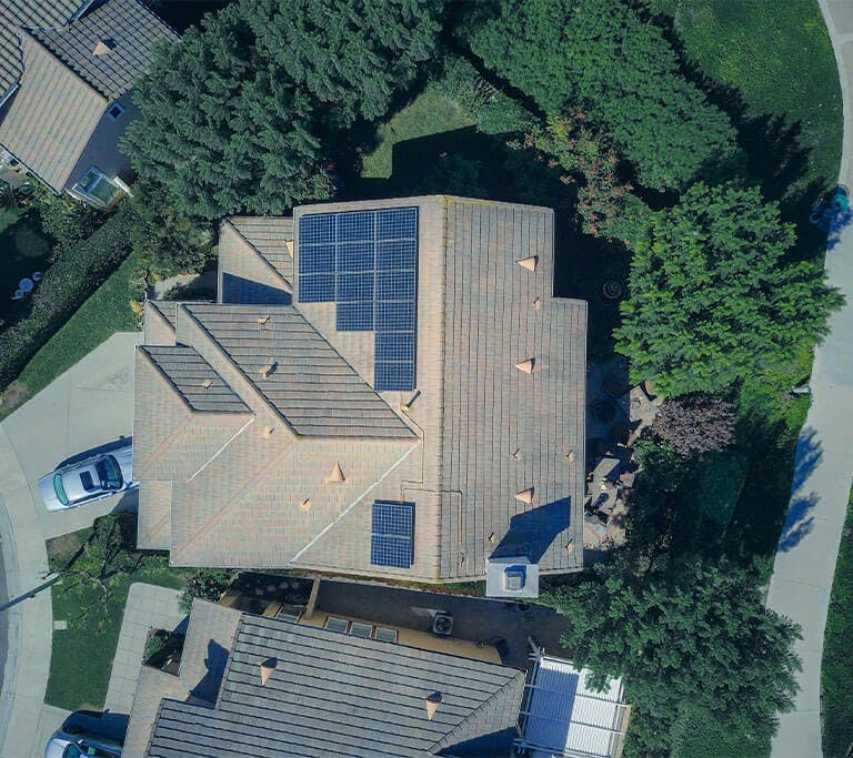 An aerial shot of houses in a neighborhood, with solar panels on top of one of the houses.