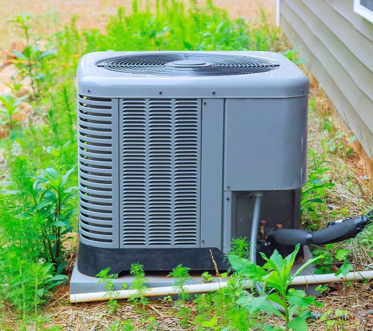 air conditioner with a SEER rating of 13 next to a white wall and beautiful landscaping.