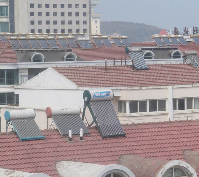 Dozens of rooftop solar water heaters have been installed on several buildings on a cloudy day.