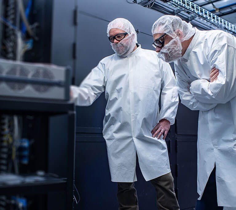 EPB and IONQ employees in protective clothing, hair covers, and goggles examine equipment in a quantum computer environment.