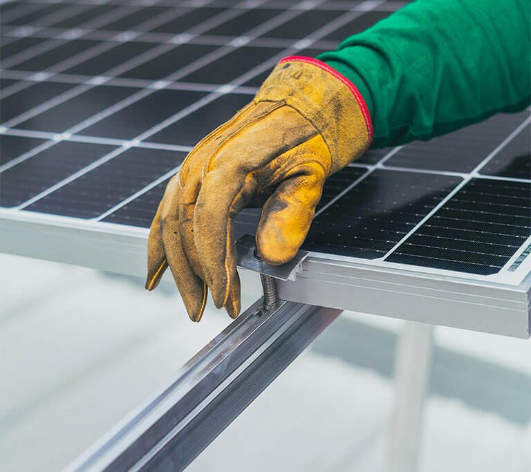 A worker securing a solar panel with a screw.