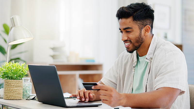 Man at laptop with credit card paying online bill