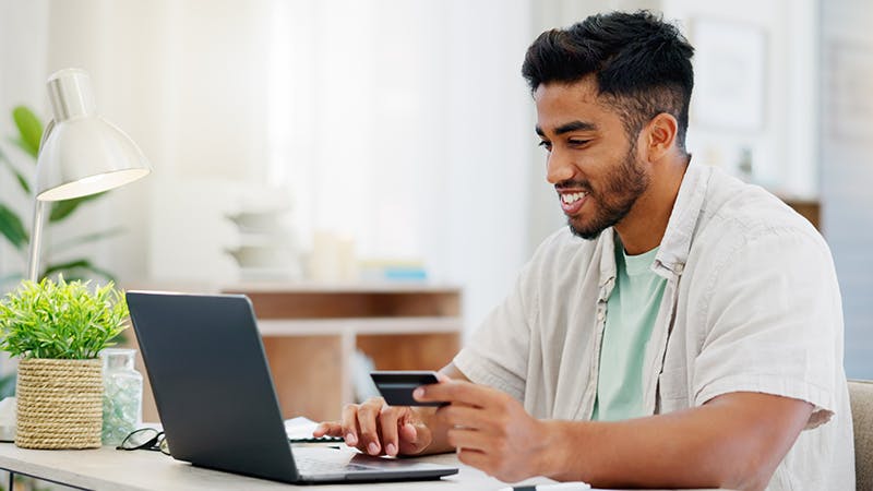 Man at laptop with credit card paying online bill