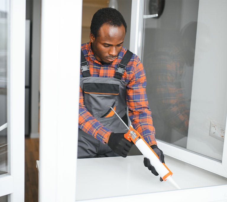 Man caulking window of home
