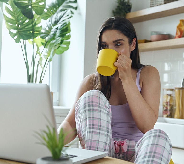 woman drinking coffee while using computer