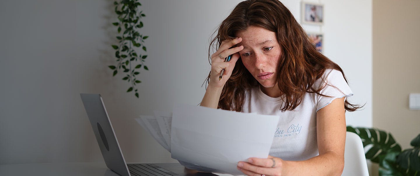 displeased-woman-reading-problematic-bills-at-home-2026-03-20-04-25-22-utc.jpg