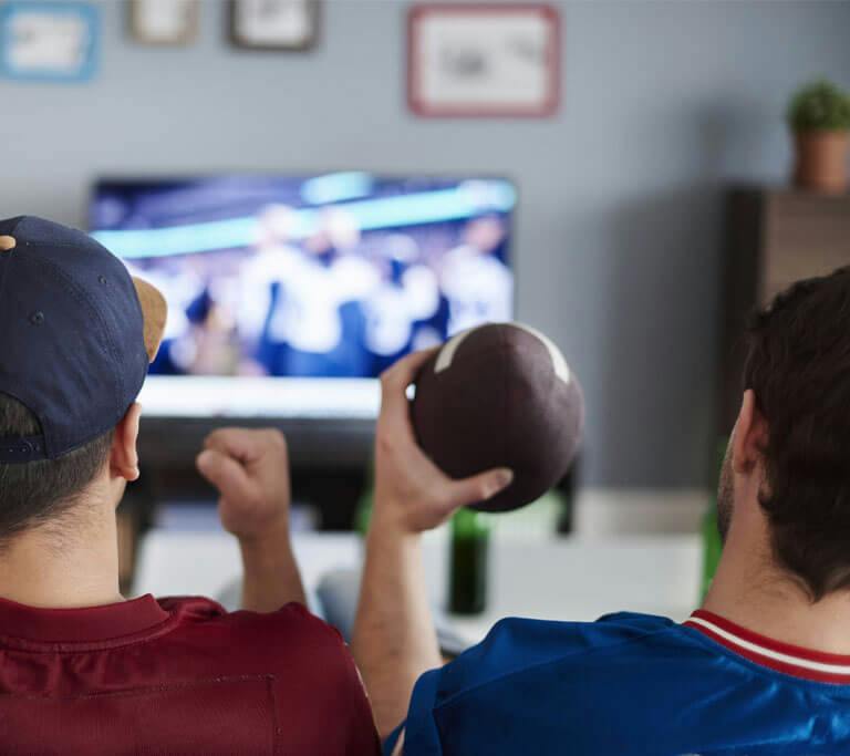 Two friends watch football on tv