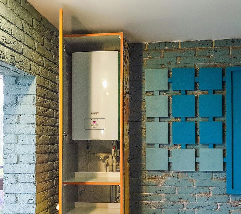 A water heater in a cabinet in a room with brick walls.