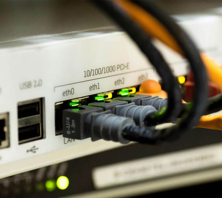 A white switch or hub is powered on and several ethernet cables are plugged into the ports.