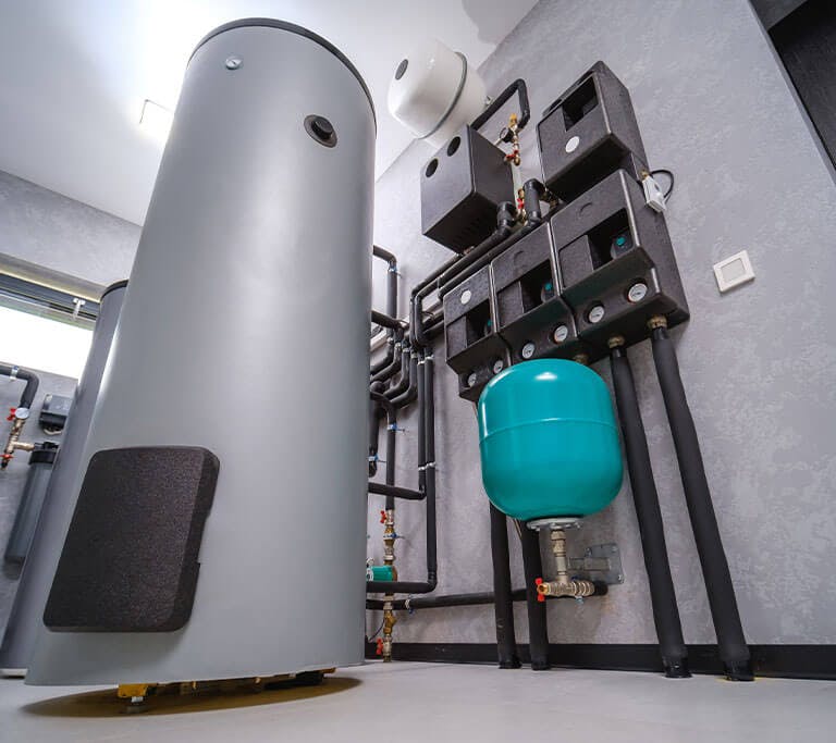 A water heater is connected to a water heater expansion tank in a white utility room.