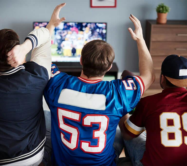 Three friends cheering at football on tv