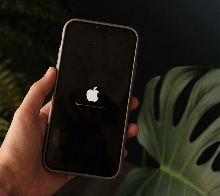 Hand holding a smartphone displaying a restart or loading screen.