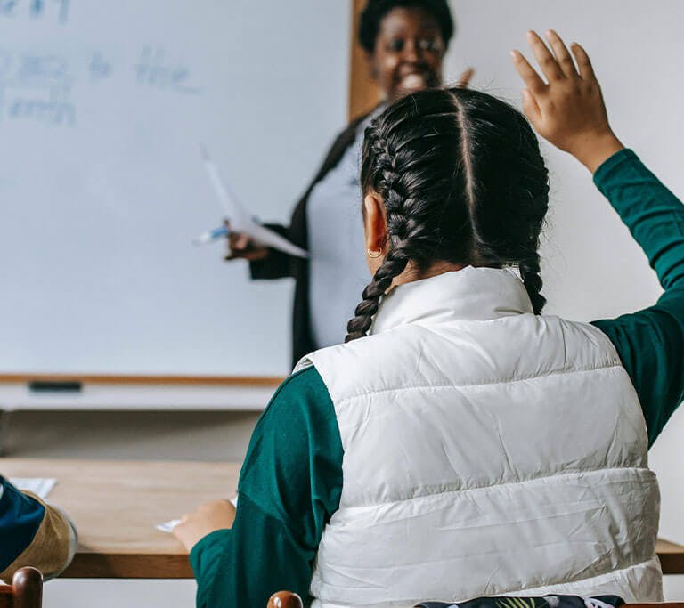A teacher calls on a student whose hand is raised to answer their question.