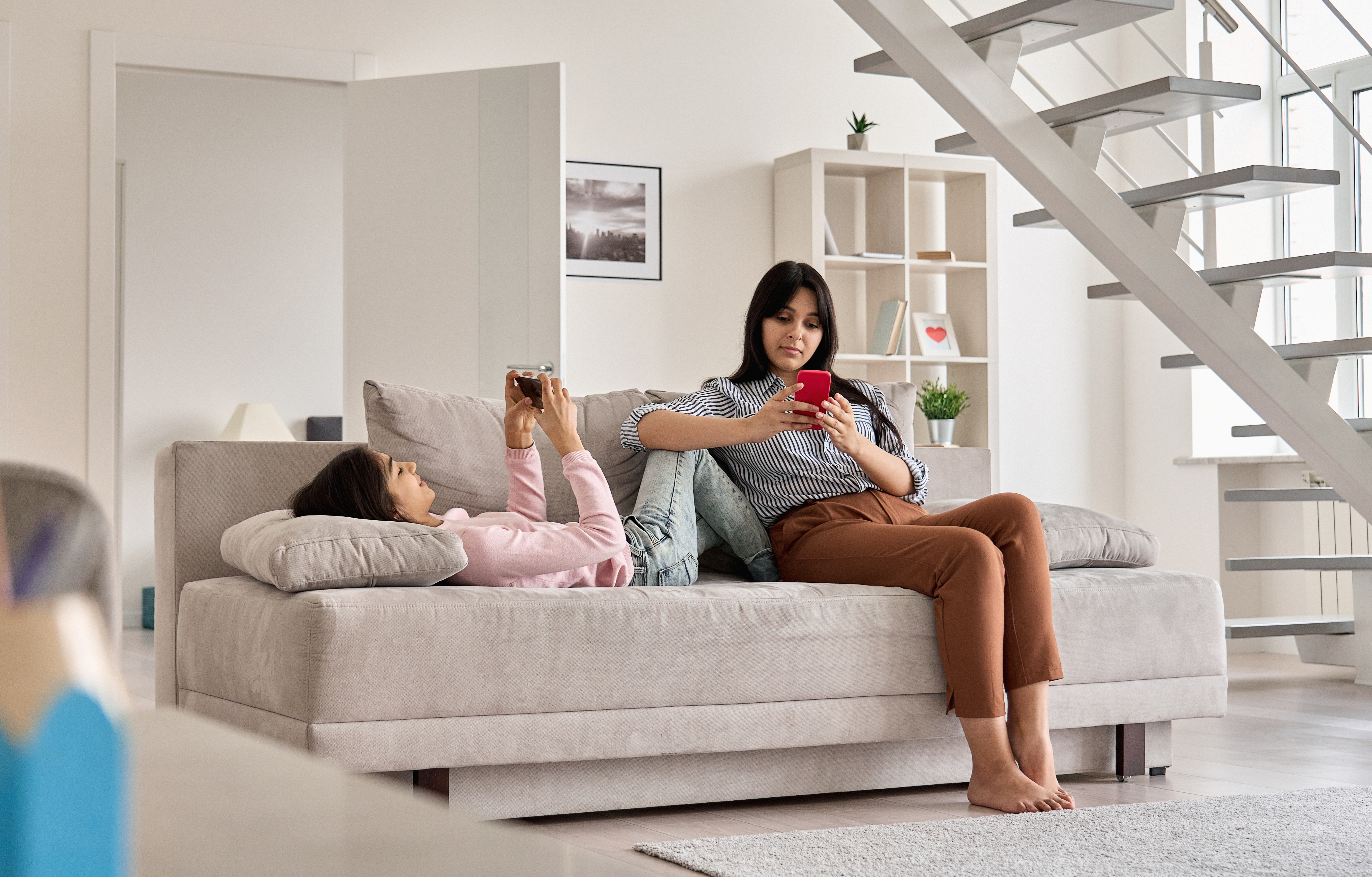 Mom and teen using devices on a sofa