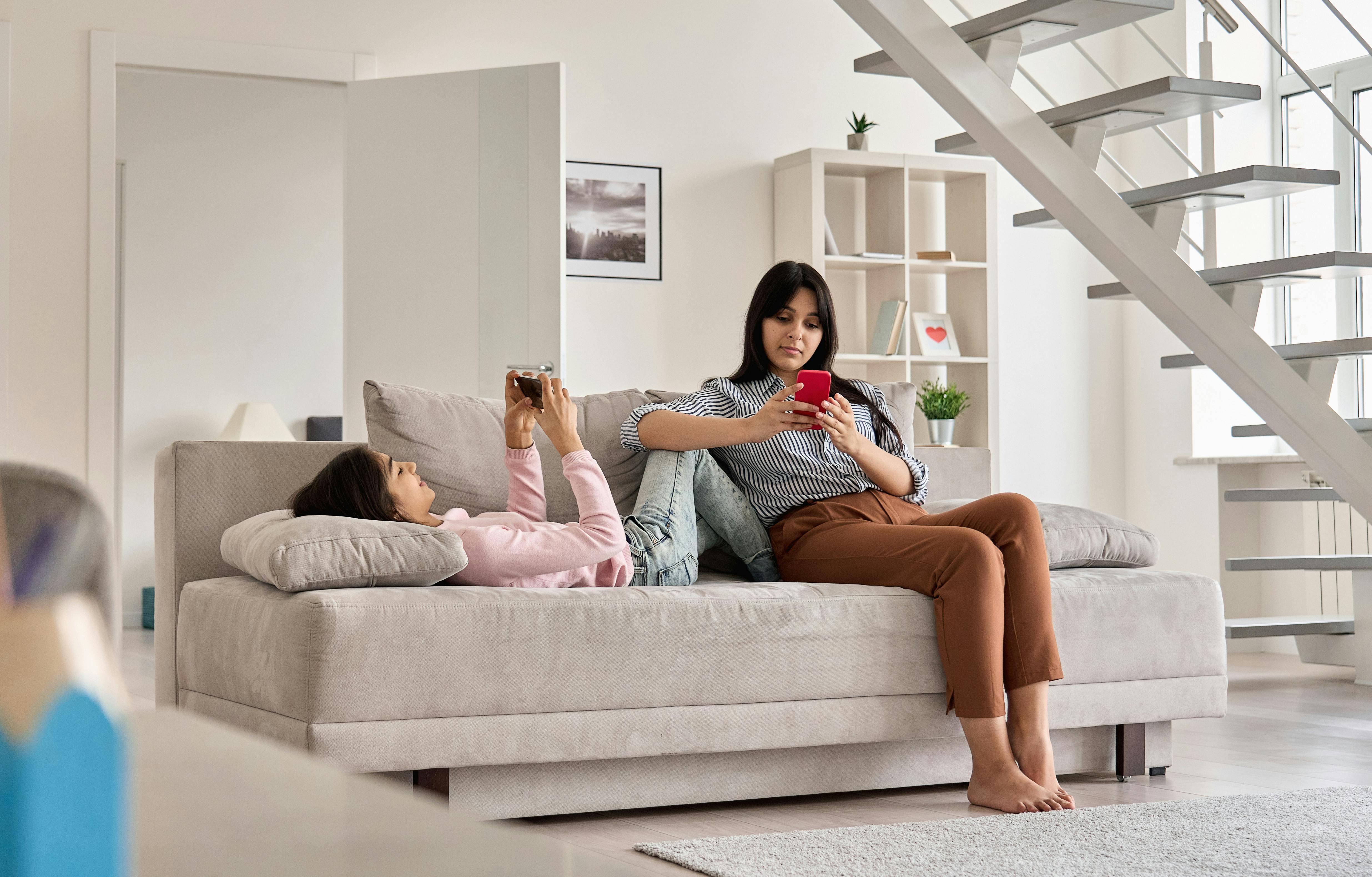 Mom and teen using devices on a sofa