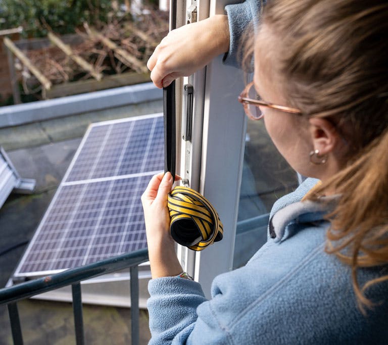woman replacing weatherstripping on door