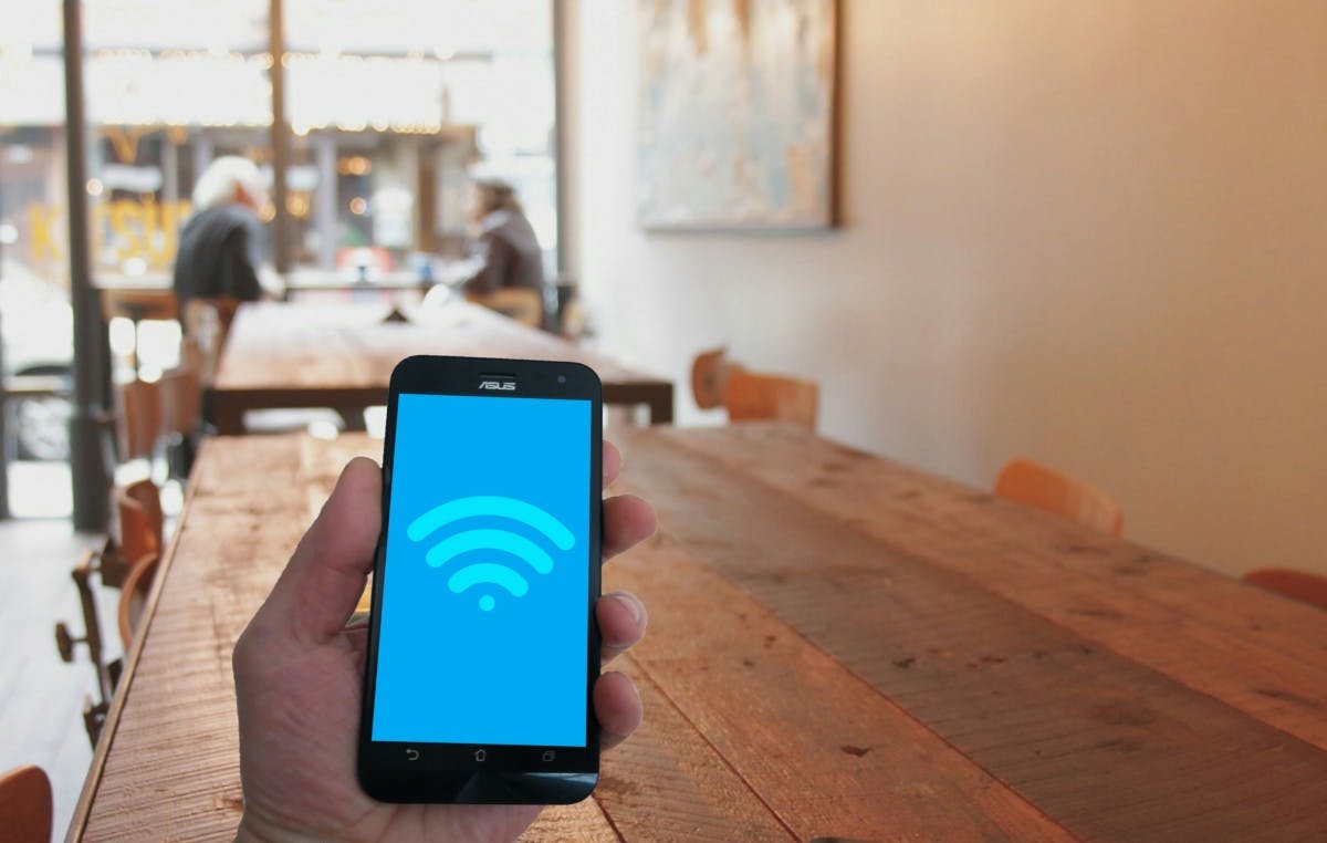 A person is looking for Wi-Fi on their phone at a cafe.